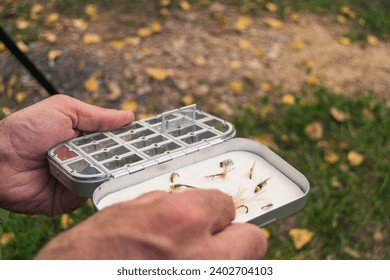 Fly fisherman chooses artificial flies from lures box for fly fishing at river - Powered by Shutterstock