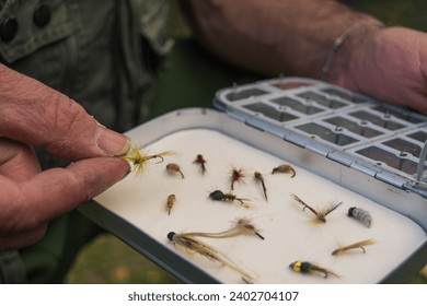 Fly fisherman chooses artificial flies from lures box for fly fishing at river - Powered by Shutterstock