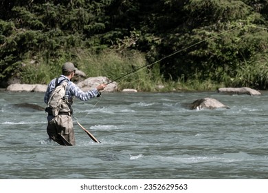 Fly fisherman fishing in the middle of the river on a summer day. - Powered by Shutterstock