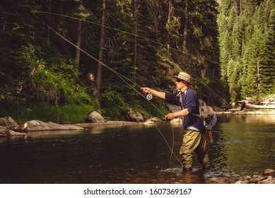 A fly fisherman fishing for wild trout on the mountain river in the forest in Northern Idaho. - Shutterstock ID 1607369167