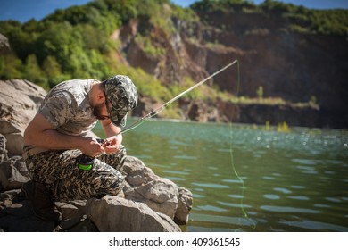 Fly fisherman using fly fishing rod on mountain lake.Replacing a lure and streamers. - Powered by Shutterstock