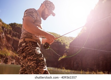 Fly fisherman using fly fishing rod on mountain lake.Replacing a lure and streamers. - Powered by Shutterstock