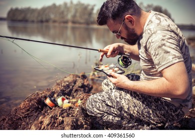 Fly fisherman using fly fishing rod on mountain lake.Replacing a lure and streamers. - Powered by Shutterstock