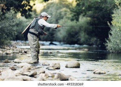 Fly fisherman using flyfishing rod in beautiful river.