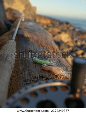 A fly fishing rod and flies for fly fishing lie on the sea rocks at sunset