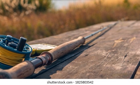 Fly fishing rod with on wood background. Autumn sunny day. - Powered by Shutterstock