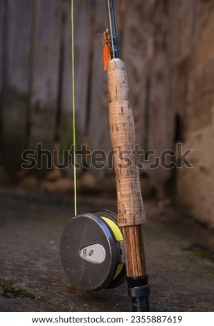 Fly fishing rod and wheel with yellow line and orange fly.
