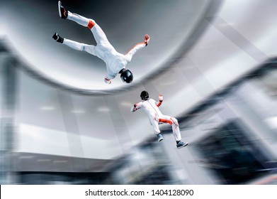 Fly Men. Sky Diving In Wind Tunnel. Indoor Sky Diving. Team Flyers. White And Orange Suit. Free Fly