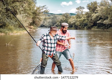 Fly Rod And Reel With A Brown Trout From A Stream. Man Fishing. Fly Fisherman Using Fly Fishing Rod In Beautiful River. Father And Son Relaxing Together