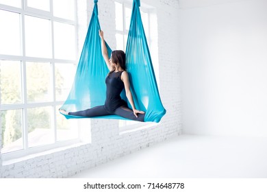 Fly yoga in a white gym. Gymnastics performs physical exercises for fly yoga, pilates, restorative health - Powered by Shutterstock