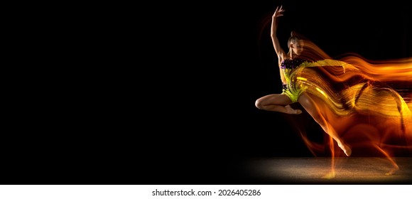 Flyer with copy space for ad. Portrait of young girl, rhythmic gymnastics artist in action isolated on dark studio background with mixed light. Concept of sport, action, aspiration, beauty and motion