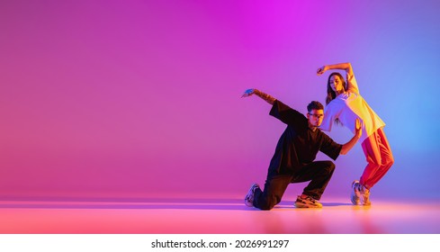 Flyer. Strange body movements. Two young people, guy and girl dancing contemporary dance over pink background in neon light. Modern dance aesthetics concept - Shutterstock ID 2026991297