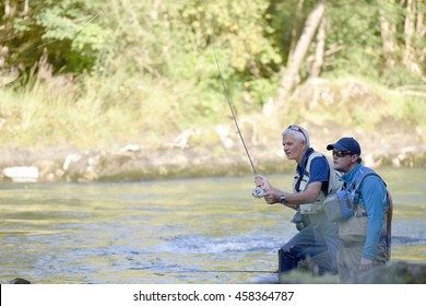 Flyfisherman With Fishing Guide In River