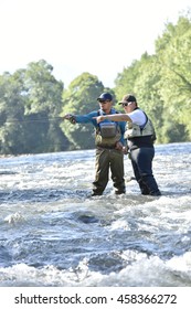 Flyfisherman With Fishing Guide In River