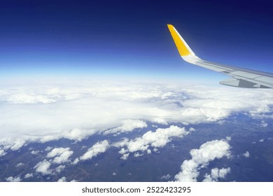 Flying above the clouds: cloudy sky and airplane wing photographed from the window of a passenger plane. The beginning of a vacation - traveling abroad by plane.