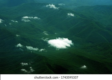 Flying Above The Clouds, Forested Mountain Landscape, Top View From The Airplane. Green Mountains
