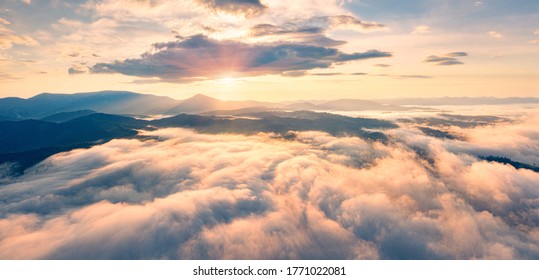Flying above the clouds on drone. Panoramic morning view of Carpathian mountains with Homiak mountain on background. Fabulous sunrise on Ukraine, Europe. Beauty of nature concept background.