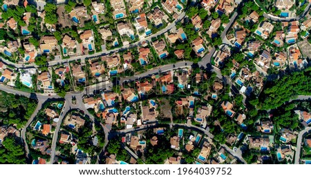 Flying above a suburban town in Spain. Red roofs in an idyllic and quiet Surbubian community with garden and waterway between house
