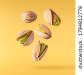 Flying in air fresh raw whole and cracked pistachios  isolated on yellow background. High resolution image