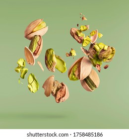 Flying in air fresh raw whole and cracked pistachios  isolated on green background. Concept of Pistachios is torn to pieces close-up. High resolution image