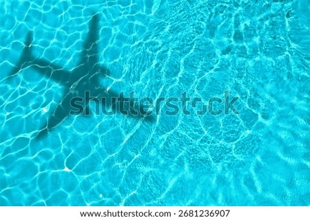 Flying airplane casting shadow on water, top view
