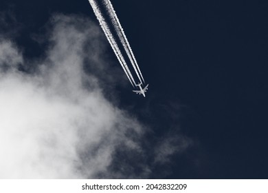 Flying airplane leaving contrails in the blue sky with clouds.