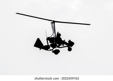 Flying autogyro silhouette on white background.