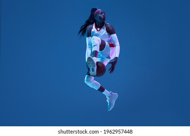 Flying. Beautiful african-american female basketball player in motion and action in neon light on blue background. Concept of healthy lifestyle, professional sport, hobby. Woman in sport. - Powered by Shutterstock