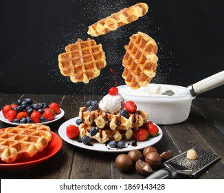 Flying Belgian Liege Waffles With Ice Cream, Berries And Topped Macadamia Nuts On Plate Powdered Sugar On Black Background. Side View.