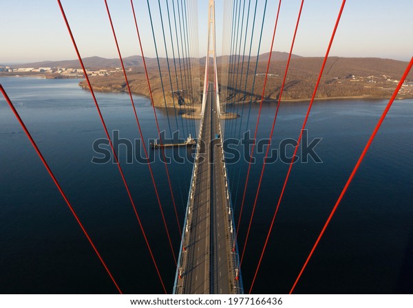 Flying between\
cables and above the road with driving cars of cable-stayed Russian\
bridge across the frozen Eastert Bosphorus strait. Aerial. Morning,\
dawning. Russia,\
Vladivostok