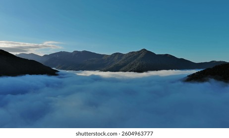 Flying between the clouds. Aerial view of clouds and mountains at sunrise. Traveling by air background