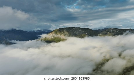Flying between the clouds. Aerial view of clouds and mountains at sunrise. Traveling by air background
