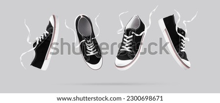 Flying black sneakers from different sides on gray background. Fashionable stylish sports casual shoes. Creative minimalistic layout with footwear.Creative template for design Mock up. Banner.