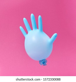 Fliegender blauer Gummi chirurgischer Handschuh als Ballon auf heißen rosa Hintergrund mit Kopienraum. Minimalismus-Konzept.