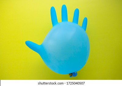 Flying Blue Rubber Surgical Glove In The Form Of A Balloon On A Yellow Background With A Copy Of Space. The Concept Of Minimalism.