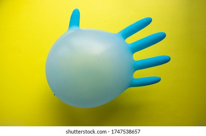 Flying Blue Rubber Surgical Glove In The Form Of A Balloon On A Yellow Background With A Copy Of Space. The Concept Of Minimalism.