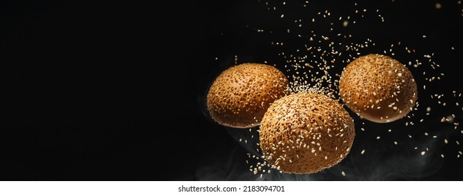 Flying burger buns with sesame seeds on black background with space for text - Powered by Shutterstock