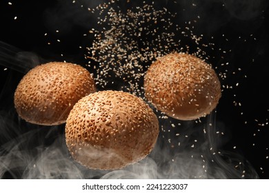 Flying burger buns with sesame and smoke on black background - Powered by Shutterstock