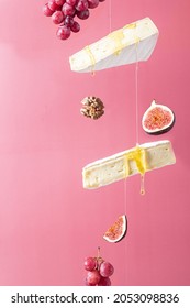 Flying cheese. Brie cheese with honey on a pink background. 