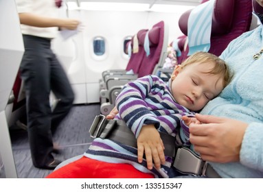 Flying With Children. Mother And Sleeping Two Year Old Baby Girl Travel On A Commercial Airliner