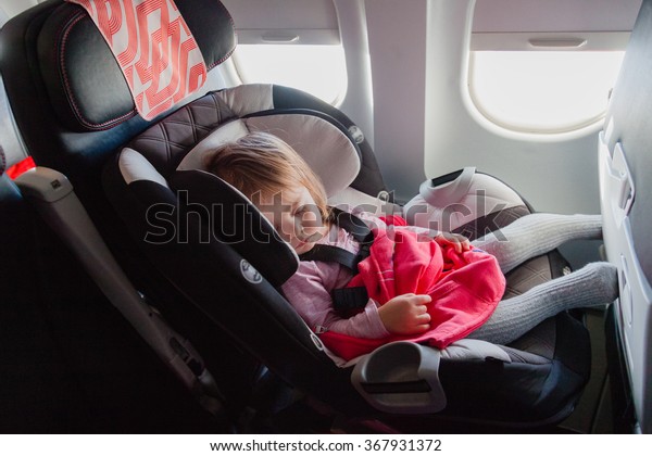 子どもと一緒に飛行 2歳の赤ちゃんが自分の車の座席で寝て 商用機の普通の座席に座る 赤ちゃんとの空の旅のコンセプト写真 自然な面内稲妻の状態 の写真素材 今すぐ編集