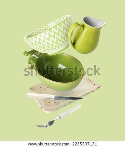 Flying clean dishes and cutlery on green background