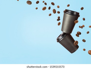 Flying coffee from a paper cups with flying coffee beans on a blue background. Coffee concept. Mockup front view. Clear plain tea take away package. Add your text.
