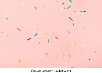 flying colorful sprinkles over pink background