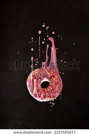 Flying donut with dripping glaze on black background,decorated with colorful dressing.Close up of sweet dessert in freeze motion.