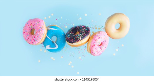 flying doughnuts - mix of multicolored sweet donuts with sprinkles on blue background