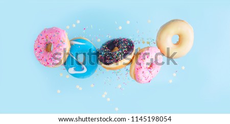 flying doughnuts - mix of multicolored sweet donuts with sprinkles on blue background
