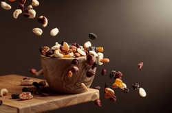 Flying Dried Fruits And Nuts. The Mix Of Nuts And Dried Berries Are In A Wooden Bowl. 