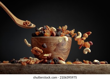 Flying dried fruits and nuts. The mix of dried nuts and raisins in a wooden bowl. Copy space. - Shutterstock ID 2106395975