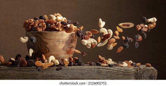 Flying dried fruits and nuts. The mix of nuts and raisins in a wooden bowl.
